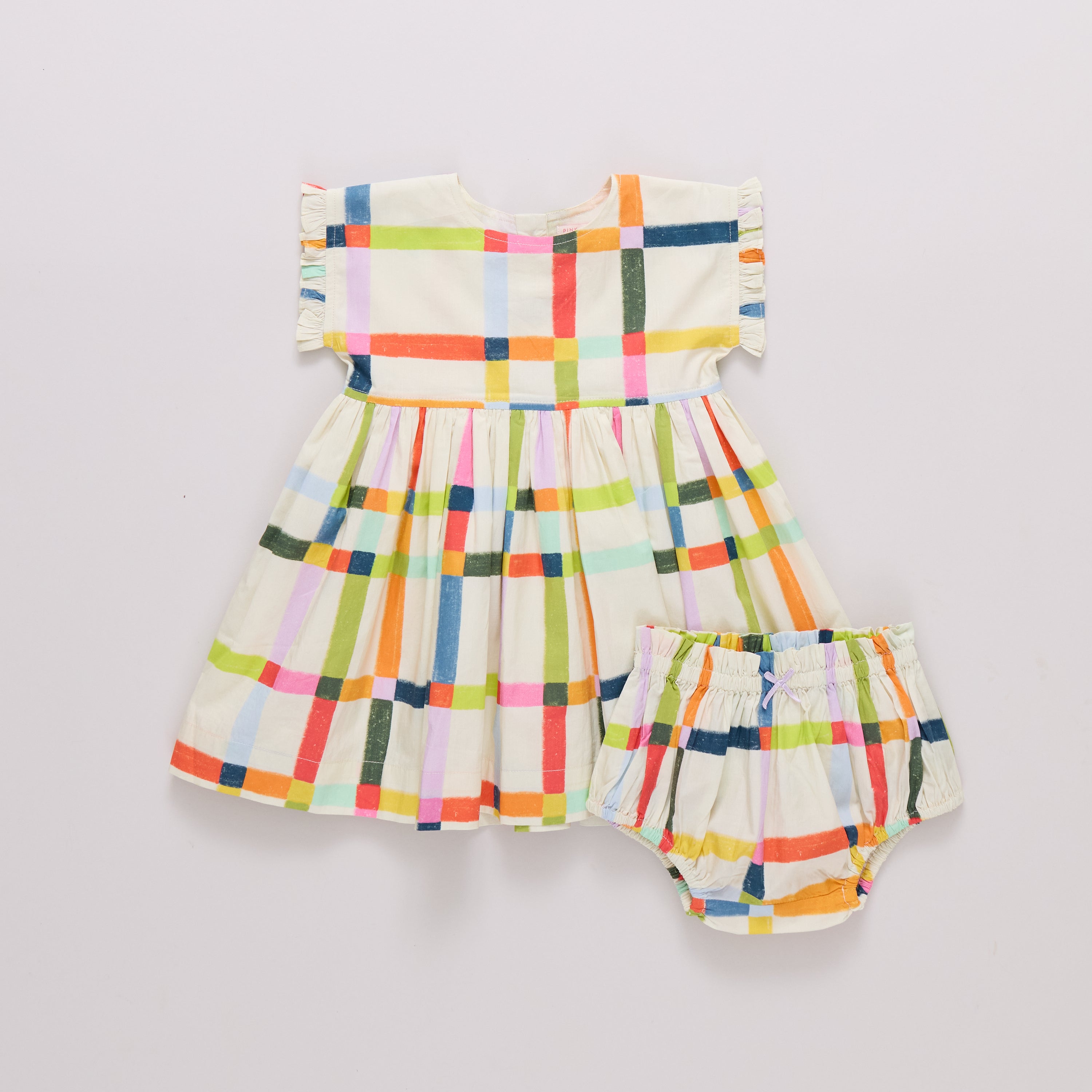 Colorful checkered baby dress and diaper set on a light gray background