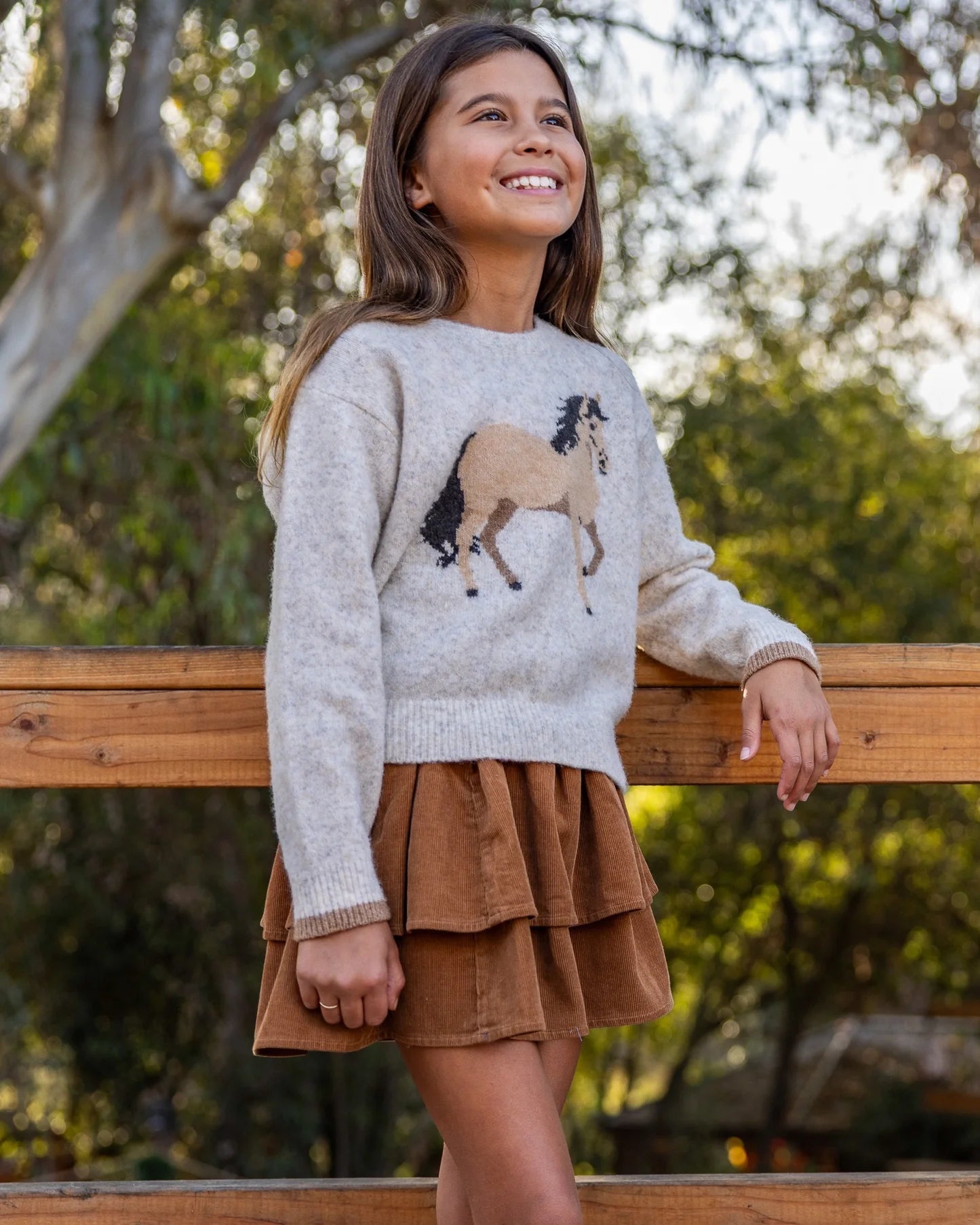 Girl wearing tiered brown corduroy skirt with a horse themed sweater