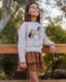 Girl wearing tiered brown corduroy skirt with a horse themed sweater