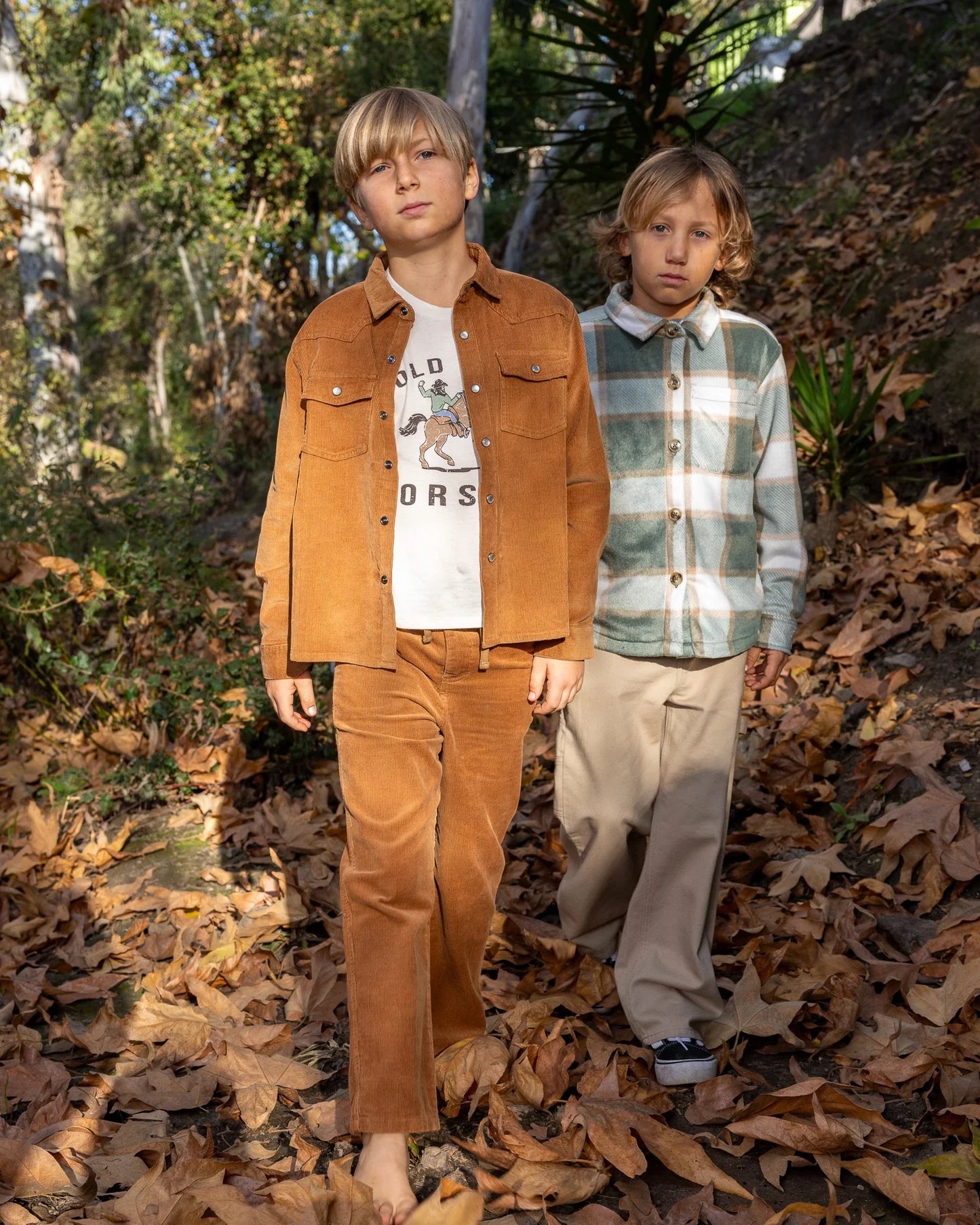 Two boys wearing casual clothes. One boy is wearing corduroy  pants with a relaxed fit and featuring an elastic waist with drawcord, side and back pockets.