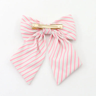 A pink and white striped fabric hair bow with a gold metal spring clip, shown on a plain white background.
