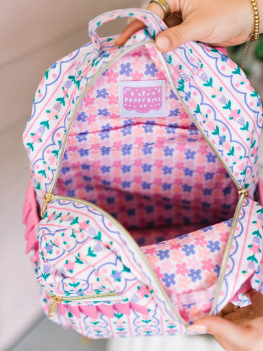 Pink floral-patterned backpack with a visible brand logo held by a person.