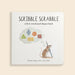 Book titled 'Scribble Scrabble' with a mouse illustration and colorful shapes on a beige background