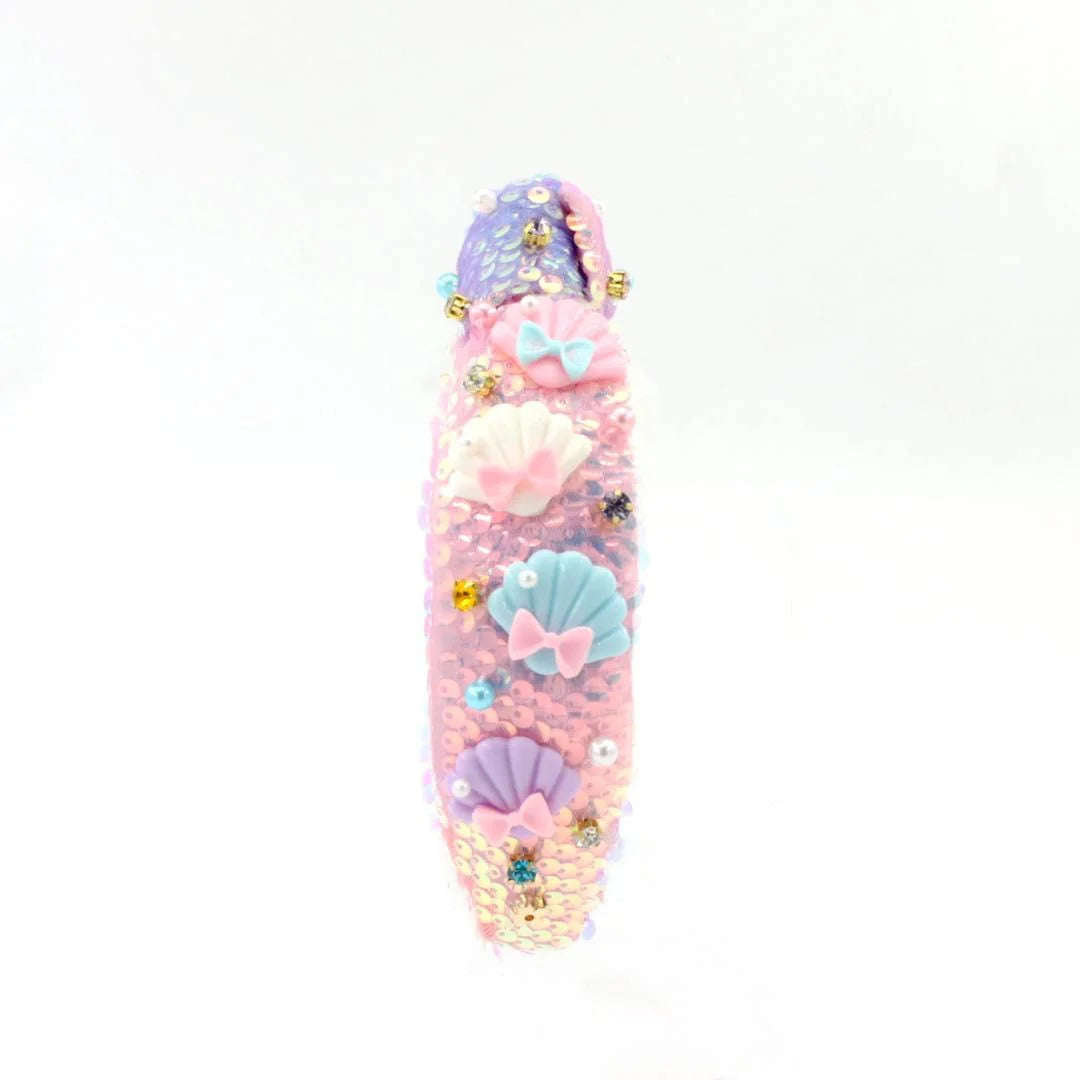 Decorative pink object with seashell and bow designs on a white background