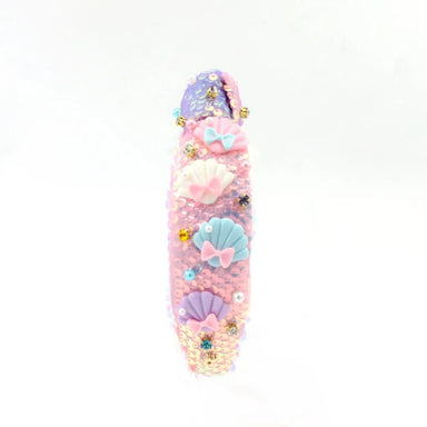 Decorative pink object with seashell and bow designs on a white background