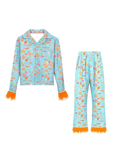 A two-piece children's pajama set featuring a light blue long-sleeve button-up top and matching pants, both printed with "Swifty"  illustrations and finished with bright orange fringed cuffs and hem.