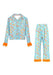 A two-piece children's pajama set featuring a light blue long-sleeve button-up top and matching pants, both printed with "Swifty"  illustrations and finished with bright orange fringed cuffs and hem.
