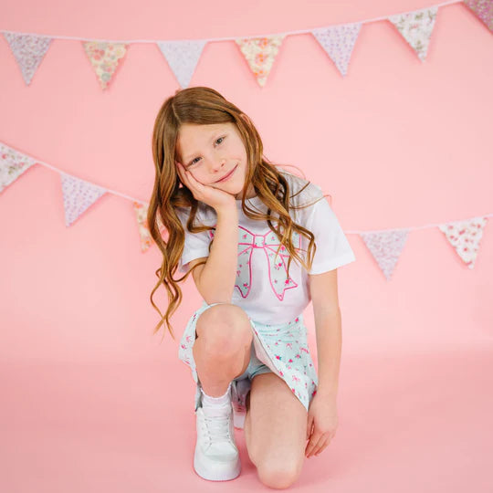 Young girl sitting on a pink floor with a decorative banner in the background