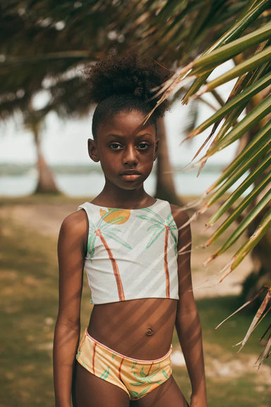 Young girl in a tropical bikini with palm leaves and a blurred background