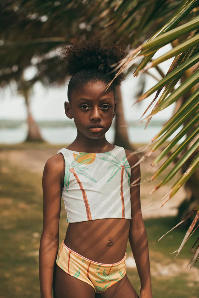 Young girl in a tropical bikini with palm leaves and a blurred background