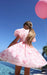 Person in a pink dress with floral pattern holding a pink balloon by a pool.