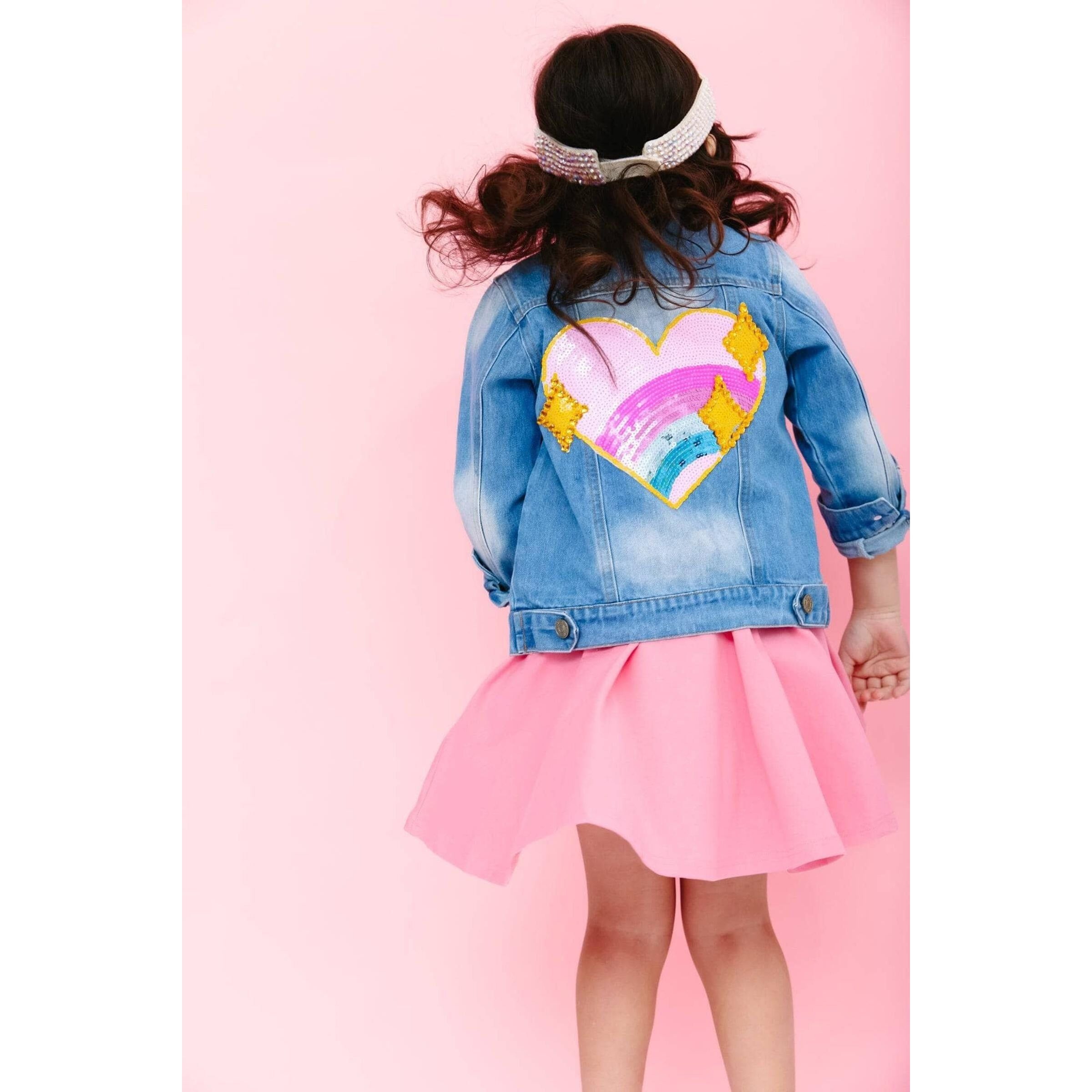 back view of girl wearing sequin sparkle rainbow heart design on back of denim jacket