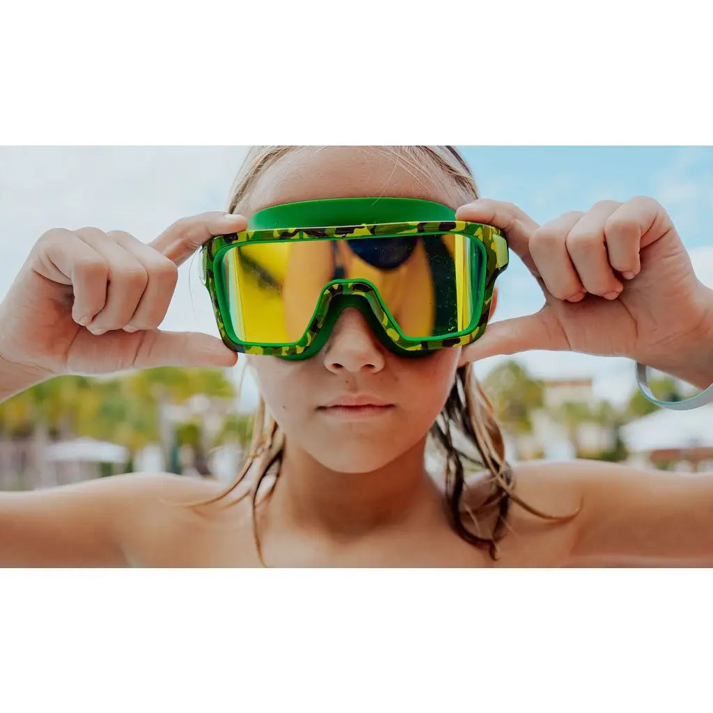 Person wearing green goggles with a blurred outdoor background