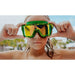 Person wearing green goggles with a blurred outdoor background