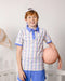 Child wearing a striped polo shirt and shorts holding a pink ball indoors.