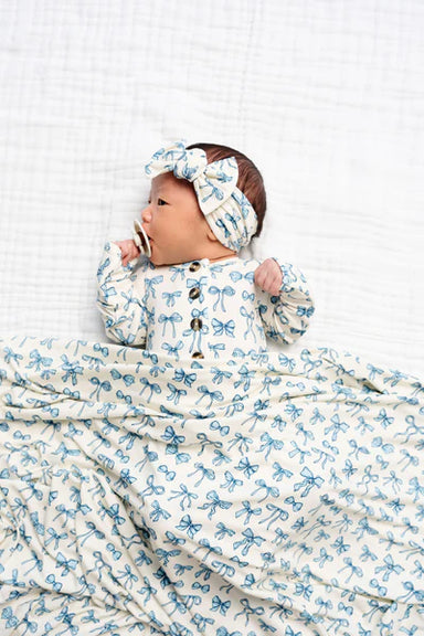 Baby swaddled in a blue and white patterned blanket with a matching headband.