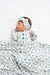 Baby swaddled in a blue and white patterned blanket with a matching headband.