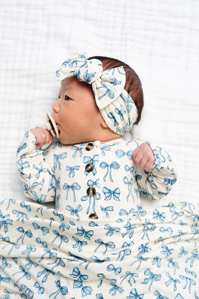 Baby wrapped in a blue and white bow-patterned blanket with a matching headband.