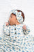 Baby wrapped in a blue and white bow-patterned blanket with a matching headband.