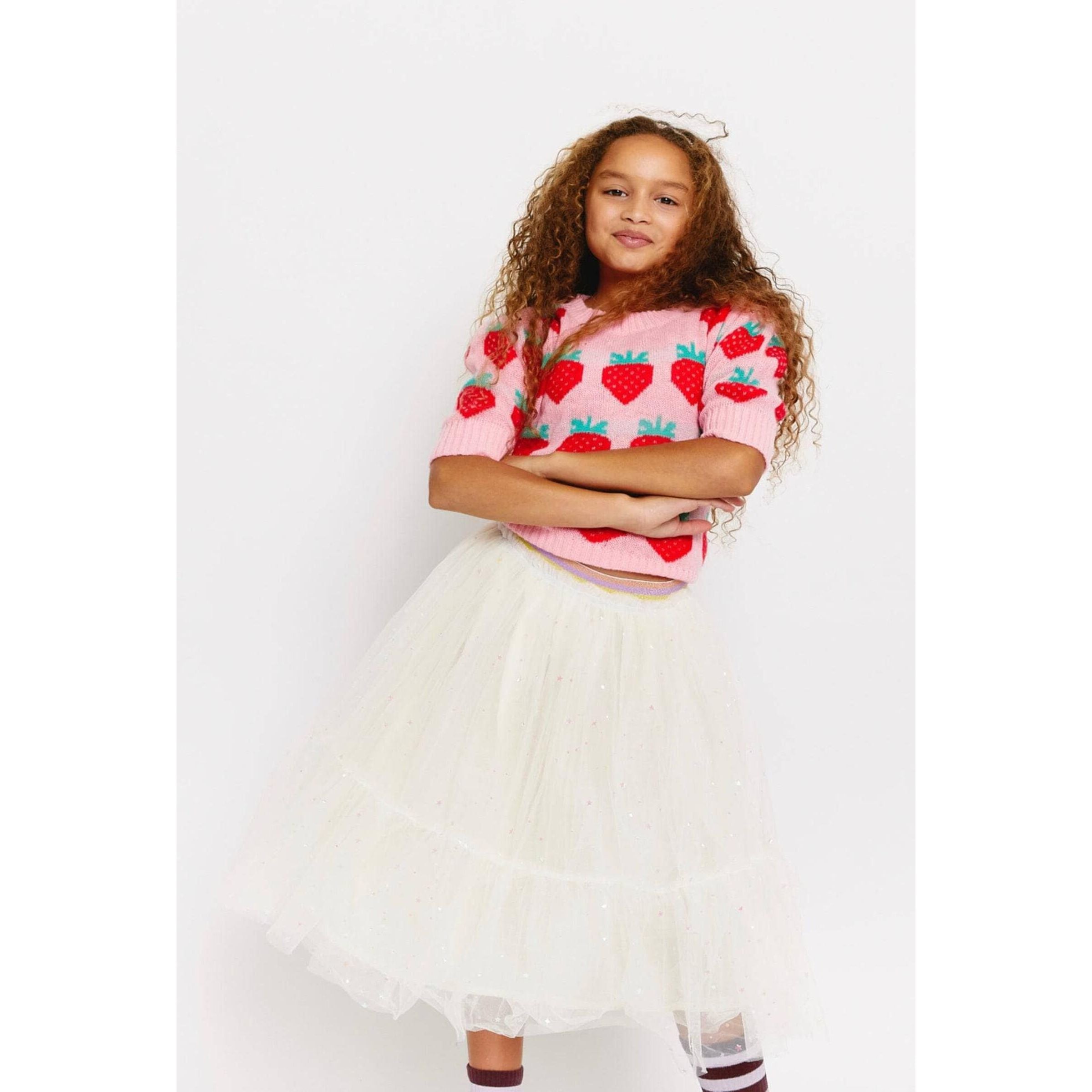 girl wearing pink puff sleeve sweater with knit strawberries and white tulle skirt