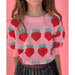 close up view of girl wearing pink puff sleeve sweater with knit strawberries
