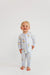 A baby wearing a light blue and white striped zip-up footless sleeper with a yellow cartoon duck print, standing against a plain white background.