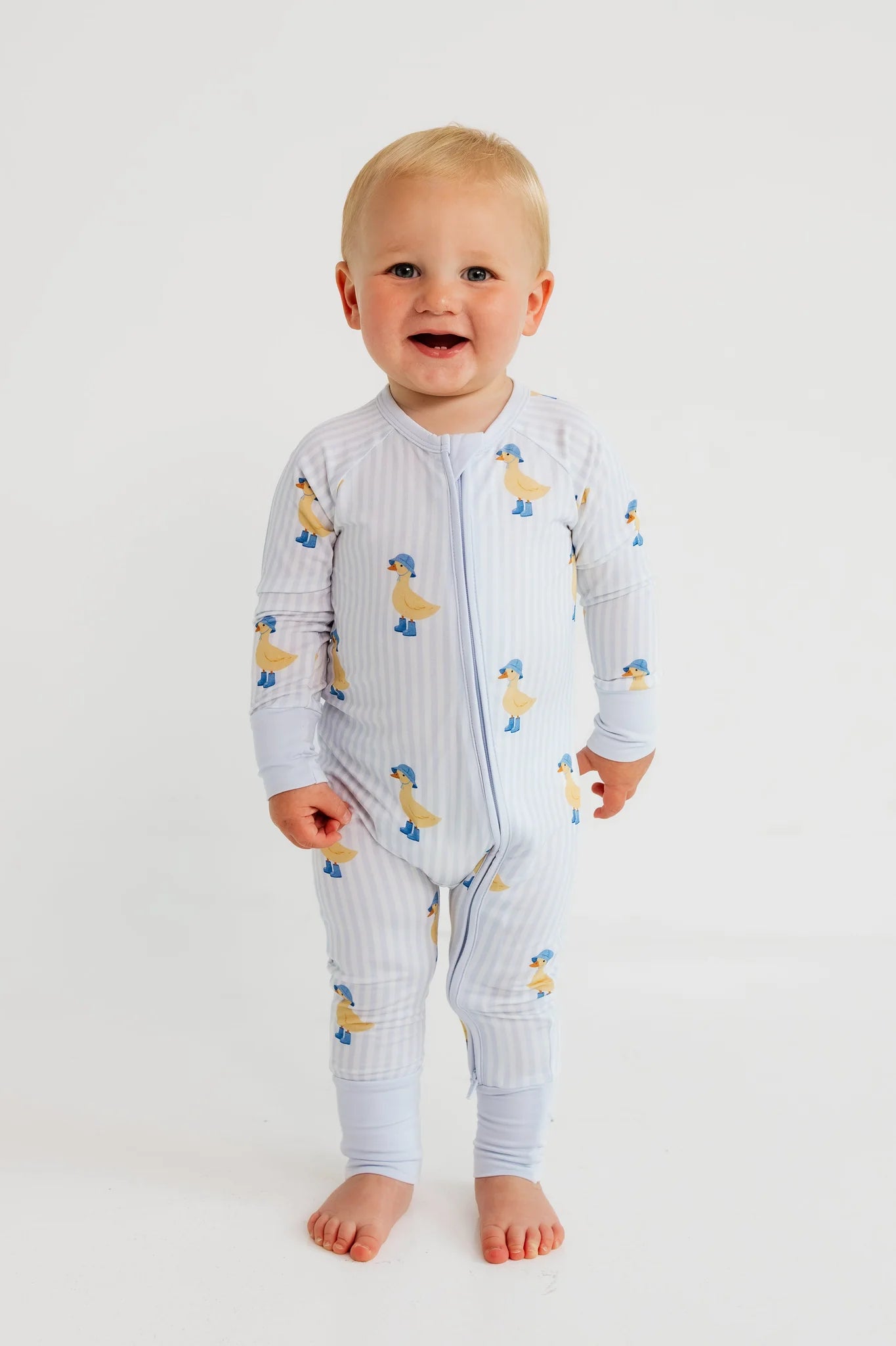 Baby wearing a light blue onesie with duck pattern on a white background