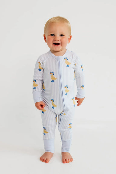 Baby wearing a light blue onesie with duck pattern on a white background