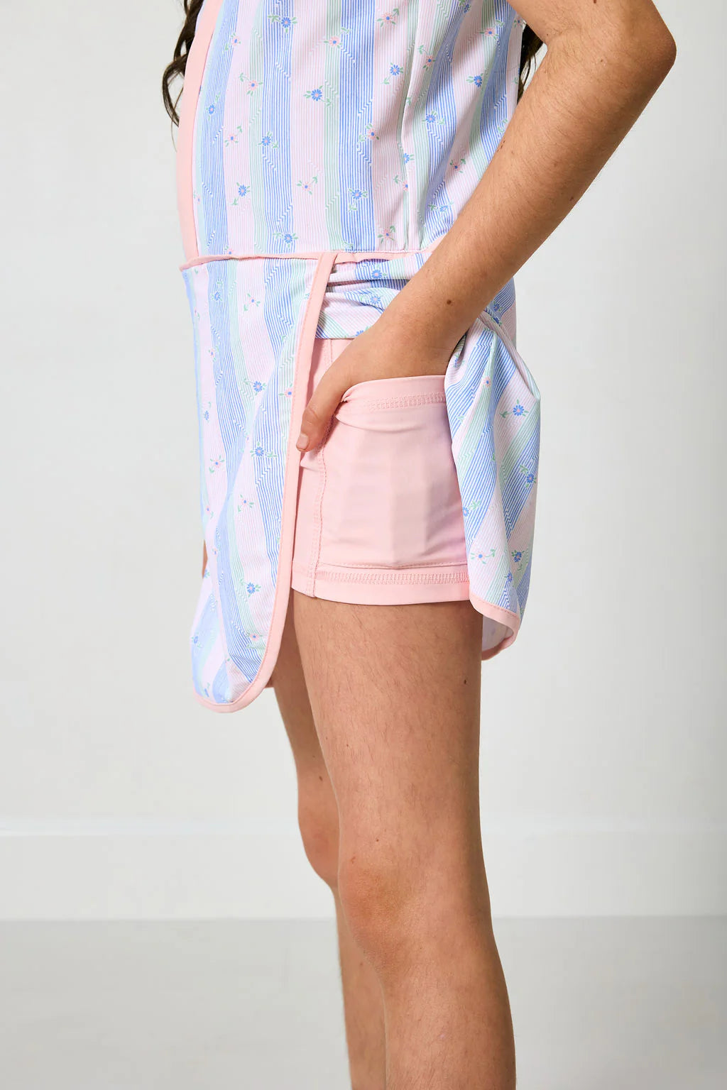 Person wearing a light blue and pink striped shirt with a matching skirt on a plain background