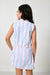 Woman wearing a sleeveless dress with blue and white striped pattern on a plain background