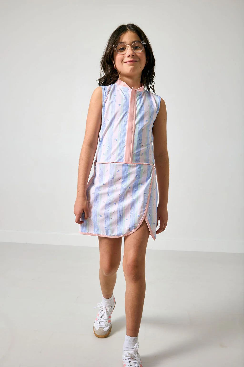 Young girl wearing a sleeveless striped dress on a white background