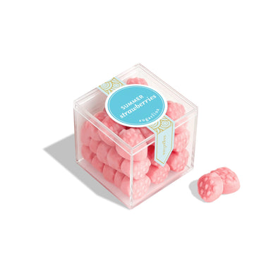 Pink strawberry-shaped candies in a clear cube with a label on a white background