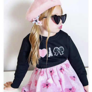 girl wearing black crewneck sweatshirt with varsity applique patches with heart, eiffel tower and bow