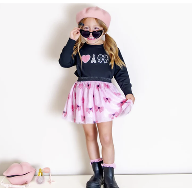 girl wearing black crewneck sweatshirt with varsity applique patches with heart, eiffel tower and bow with matching pink bow tutu skirt
