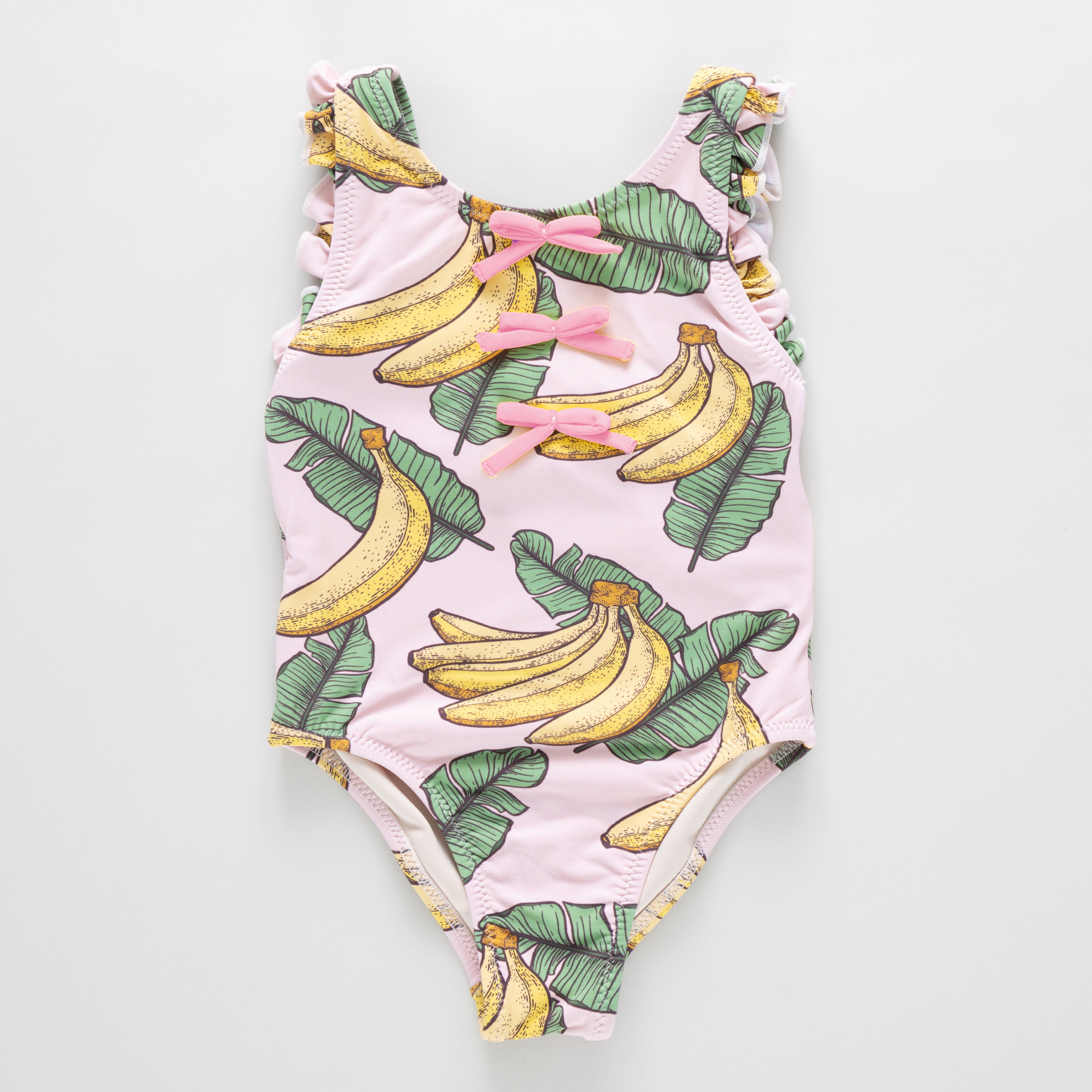 One-piece swimsuit with banana and leaf pattern on a light pink background
