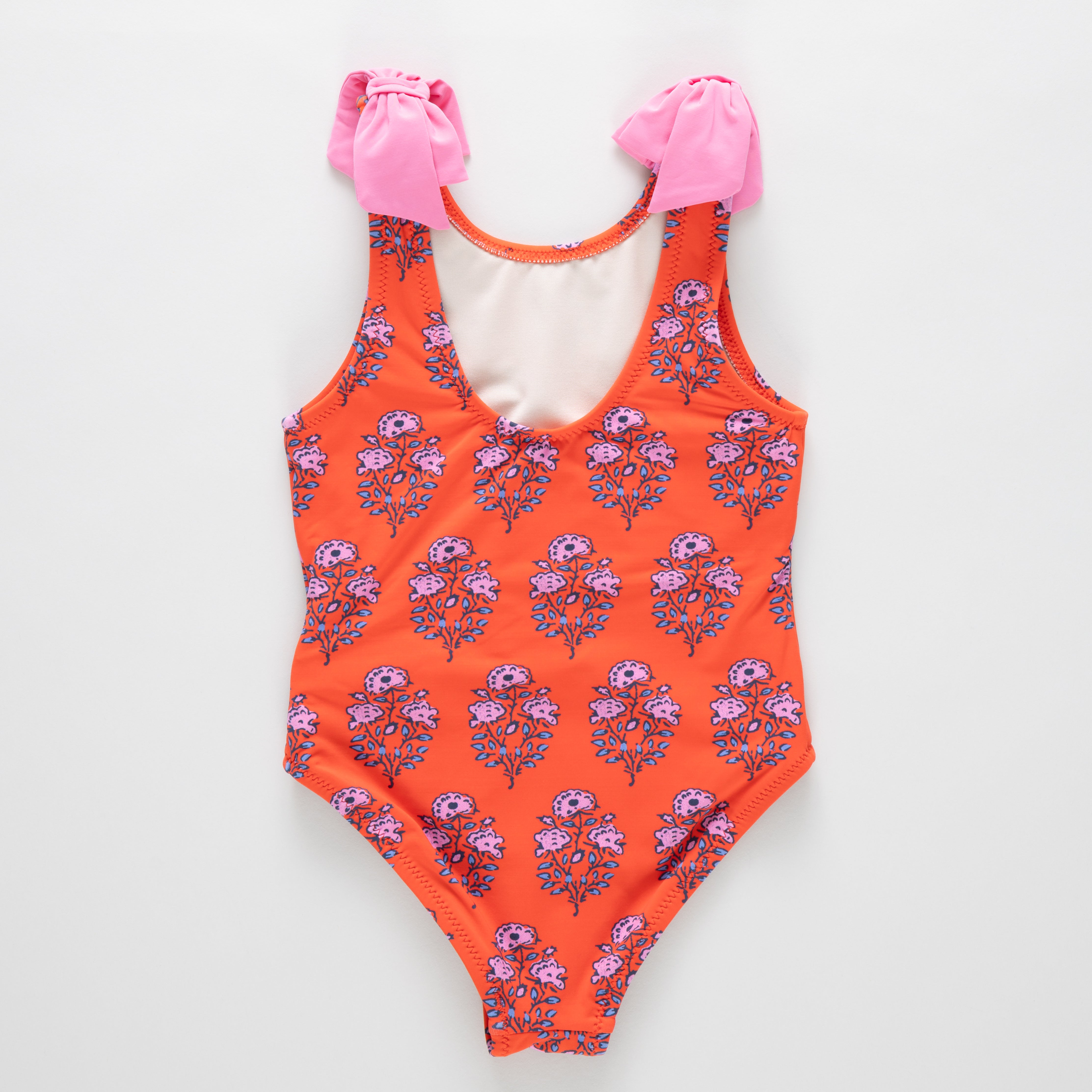 Floral-patterned swimsuit with pink accessories on a white background