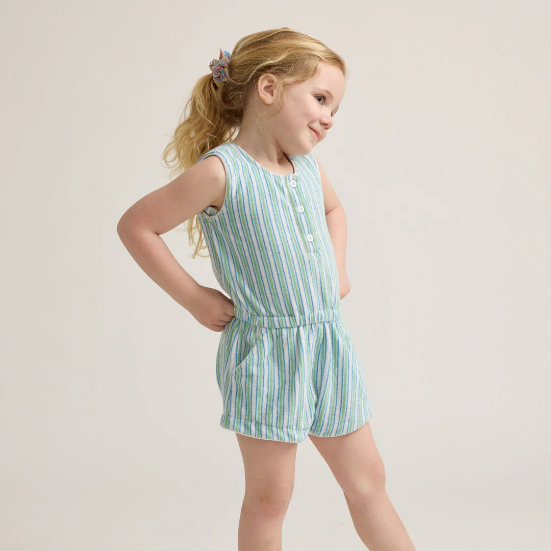 Young girl wearing a green and white striped romper on a plain background