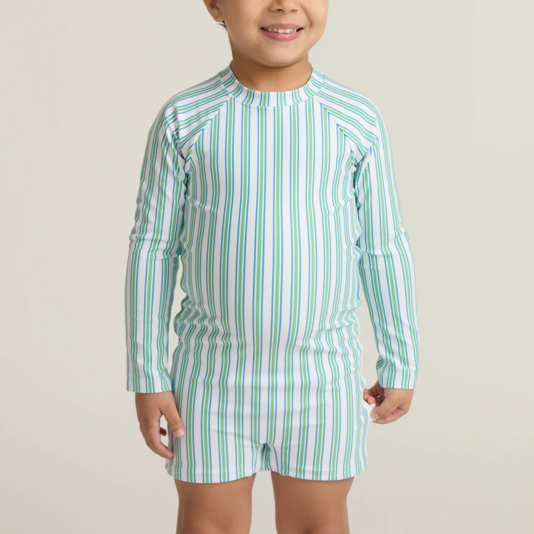 Child wearing a green and white striped swimsuit on a beige background