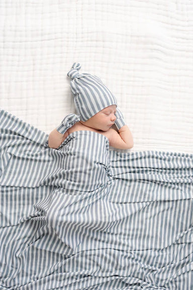 Newborn baby wrapped in grey and white striped blanket and hat on white background