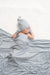 Newborn baby wrapped in grey and white striped blanket and hat on white background