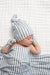 Newborn baby wrapped in a grey and white striped blanket and hat on a white textured background