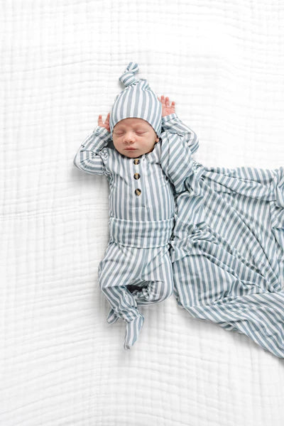 Newborn baby in grey and white striped outfit on a white textured blanket