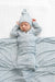Newborn baby wrapped in a grey and white striped swaddle blanket with matching hat on a white background