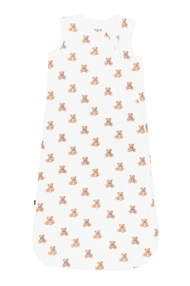 A sleeveless baby sleep sack with a white background and an all-over repeating pattern of teddy bears in orange and blue, shown flat against a white background.