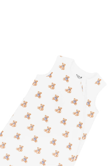 A white sleeveless baby sleep sack featuring a repeating pattern of small teddy bears wearing blue outfits, shown on a plain white background.