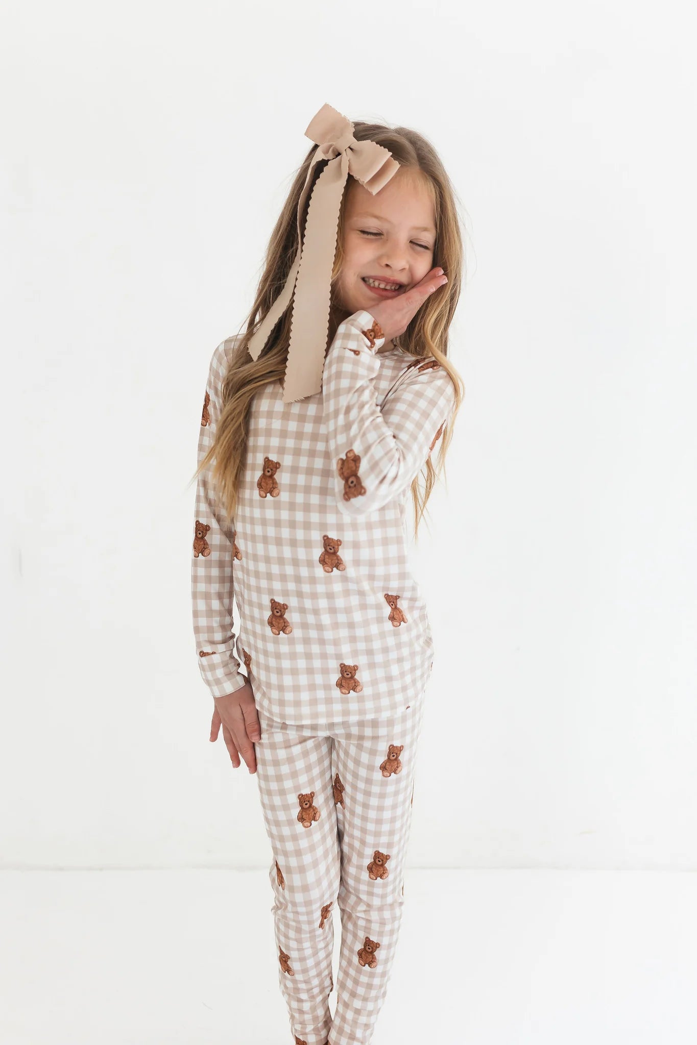 Young girl wearing a checkered outfit with bear patterns on a white background
