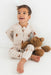 Child wearing a checkered outfit with teddy bear design, sitting on a white background