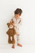 Child in checkered pajamas holding a teddy bear against a white background