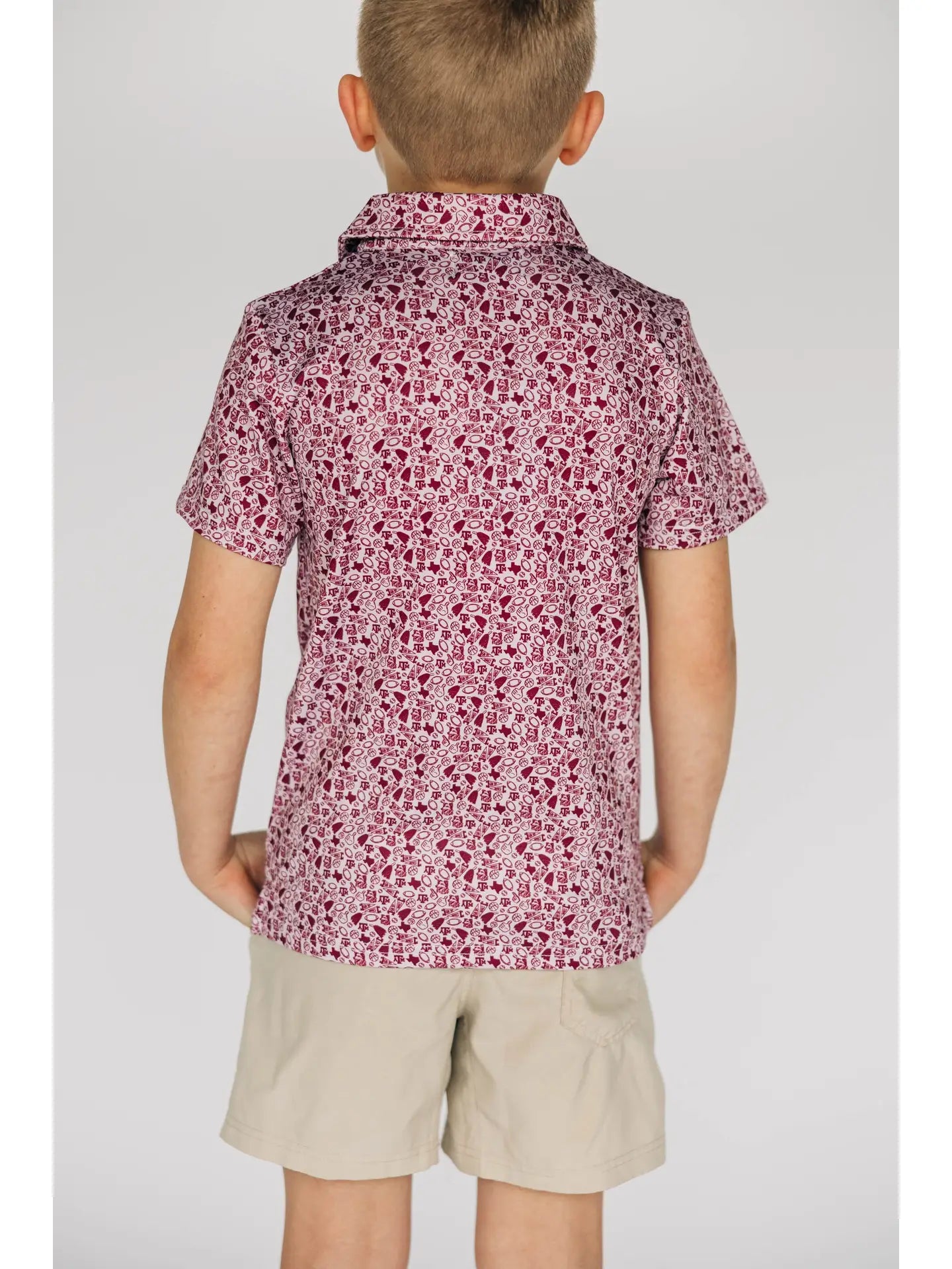 Child wearing a patterned shirt and beige shorts on a plain background