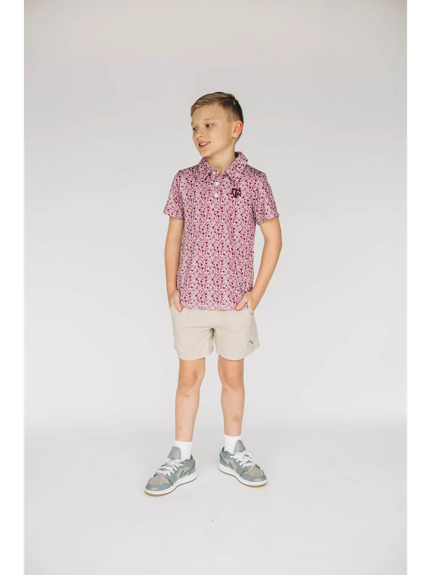 Young boy wearing a patterned shirt and shorts on a plain background